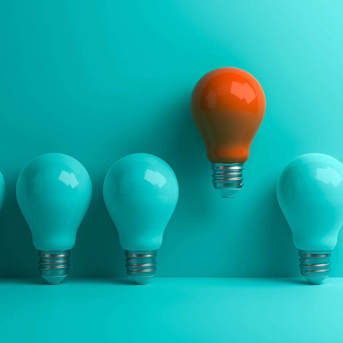 One orange light bulb standing out from a row of teal bulbs
